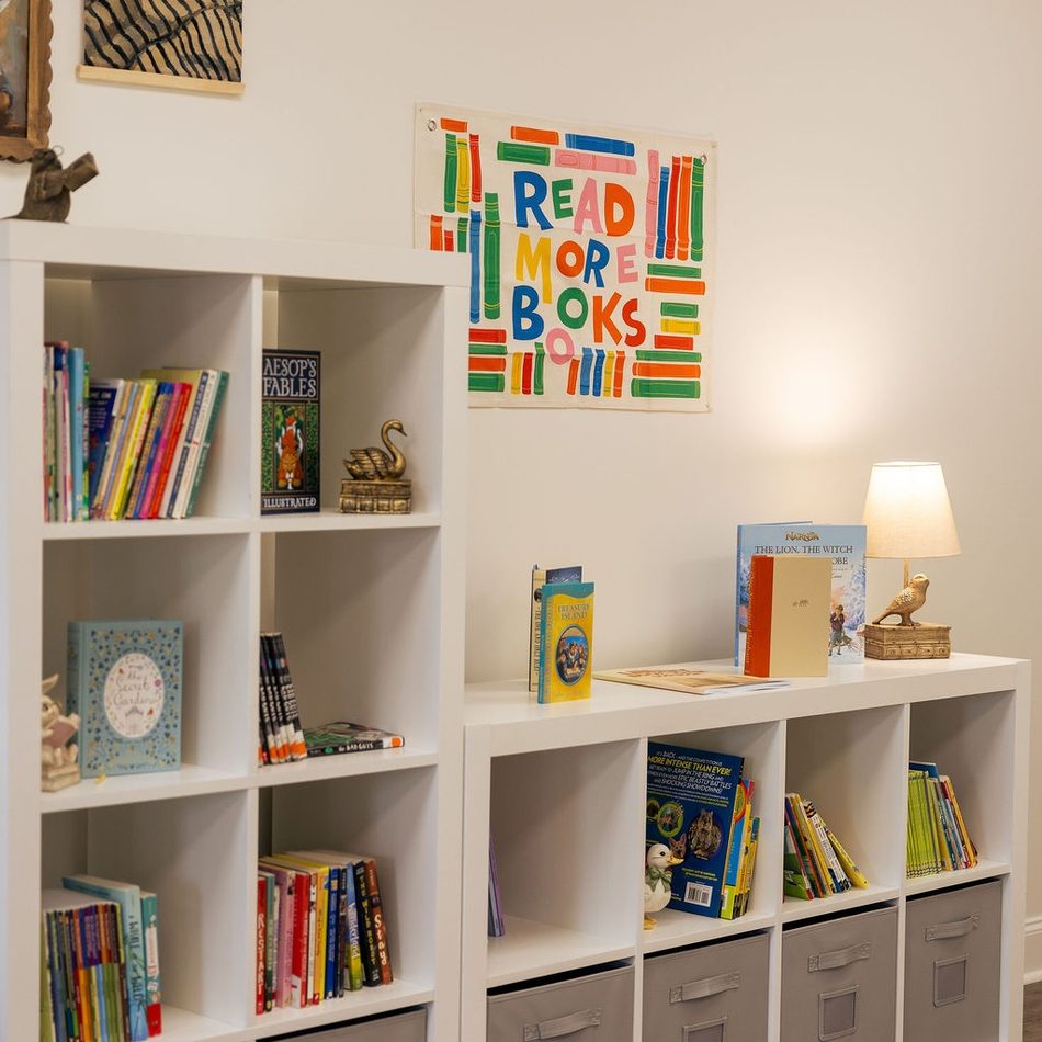 Classroom bookshelves filled with picture books beneath a Read More Books print