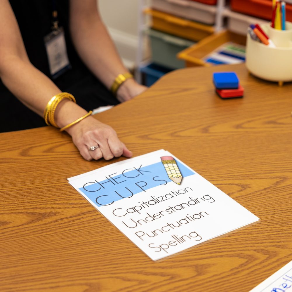 A CUPS editing card - capitalization, understanding, punctuation, spelling - on the writing table