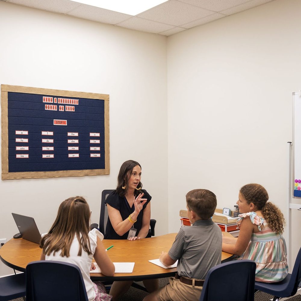A teacher works with a small group of children around a classroom table